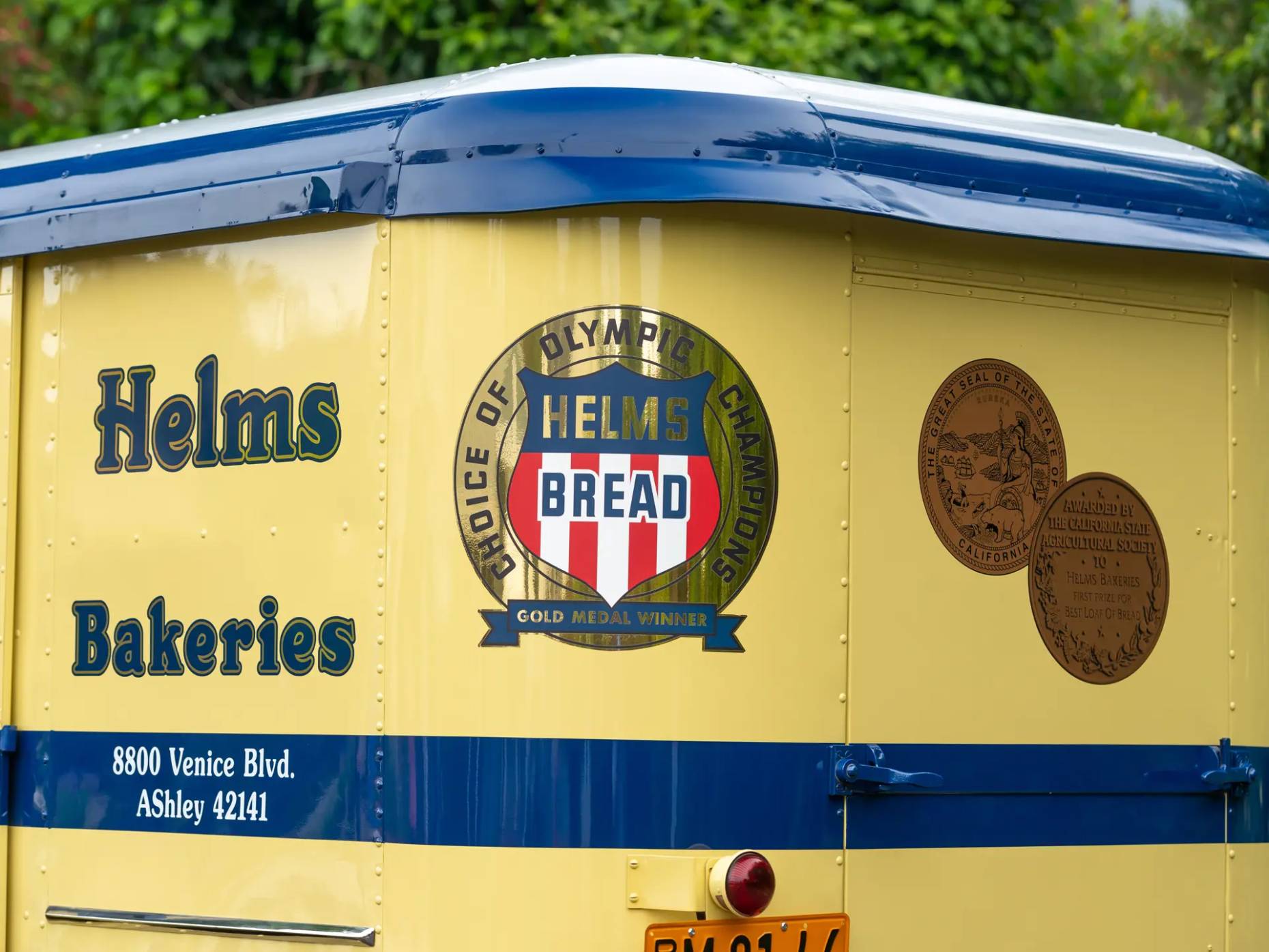 Signage on the 1936 Helms Coach, showing the Helms Bakeries name and a logo reading "HELMS BREAD: Choice of Olympic Champions: Gold Medal Winner"