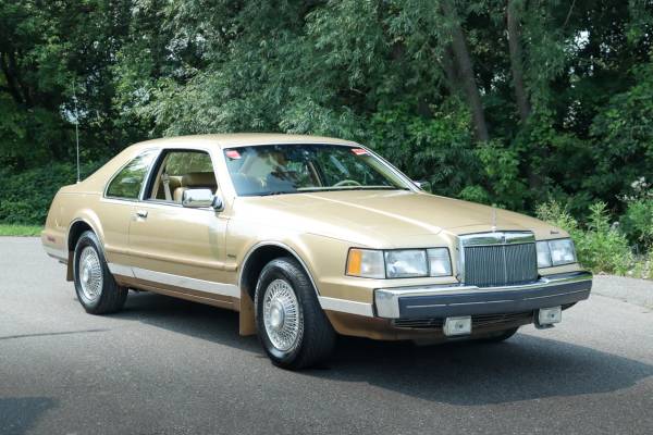 Imagem da Lincoln Mark VII de 1984 em dourado estacionada em um ambiente externo