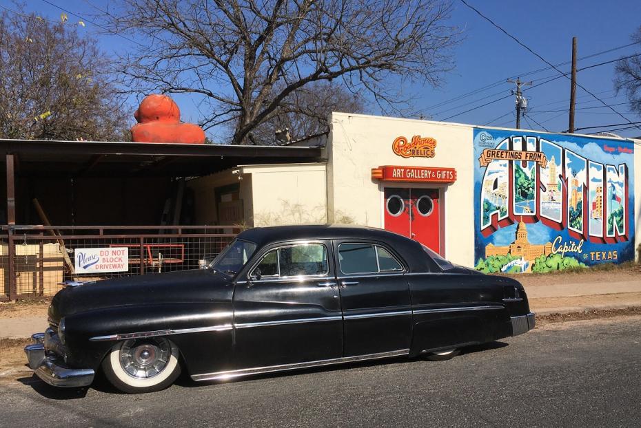 سيارة ميركوري إيت منخفضة من عام 1951 متوقفة بجوار لافتة تحيات أوستن.