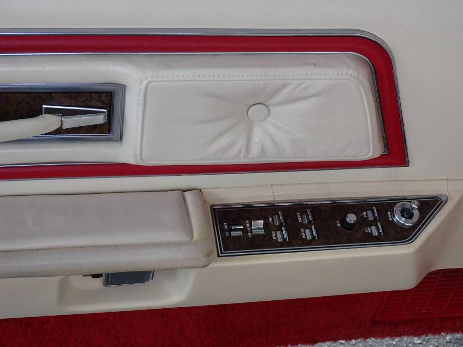 Close-up do painel da porta do condutor de um Mark IV de 1975 com detalhes em Lipstick Red sobre branco